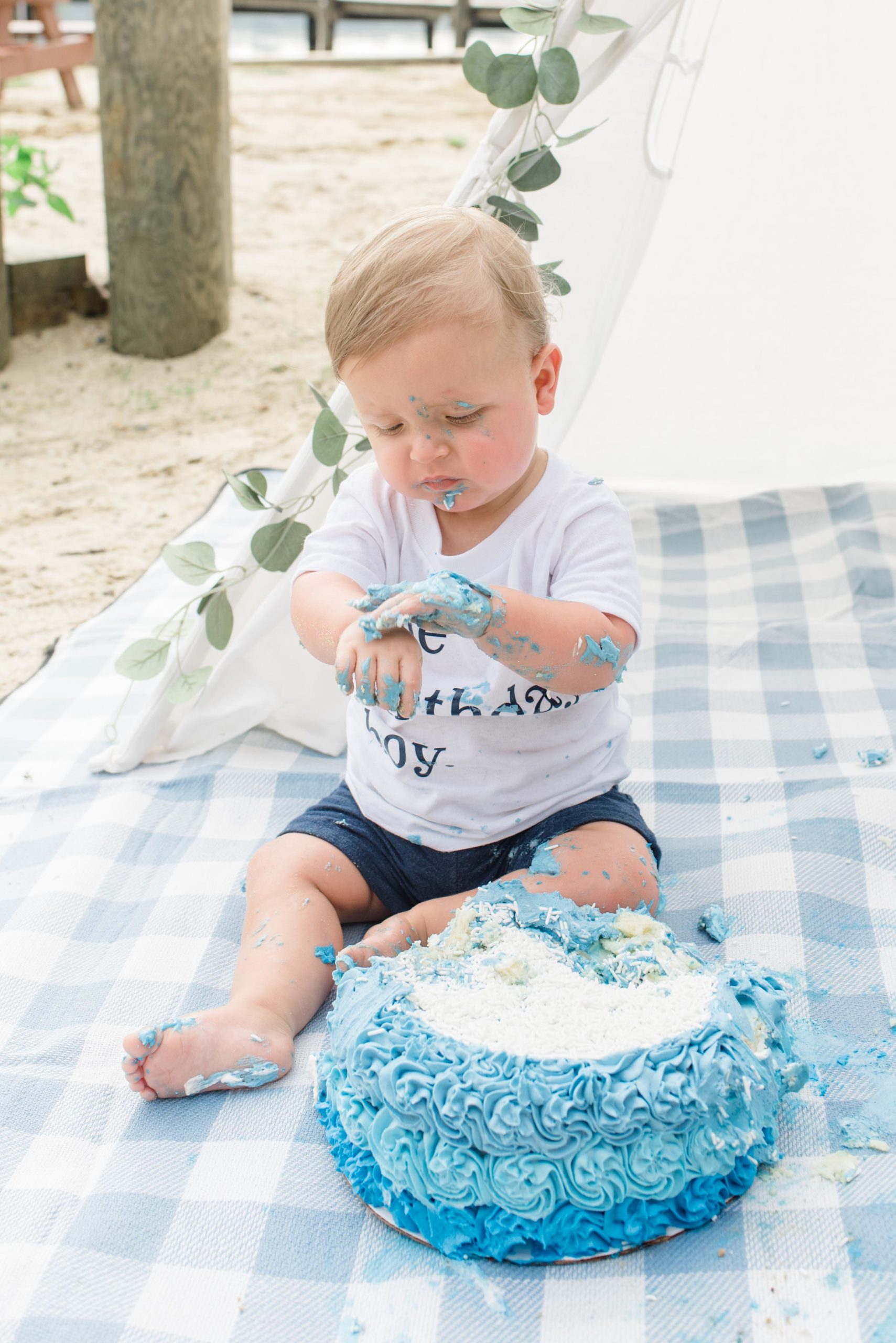 Maddox is playing with his cake during his beach first birthday session!