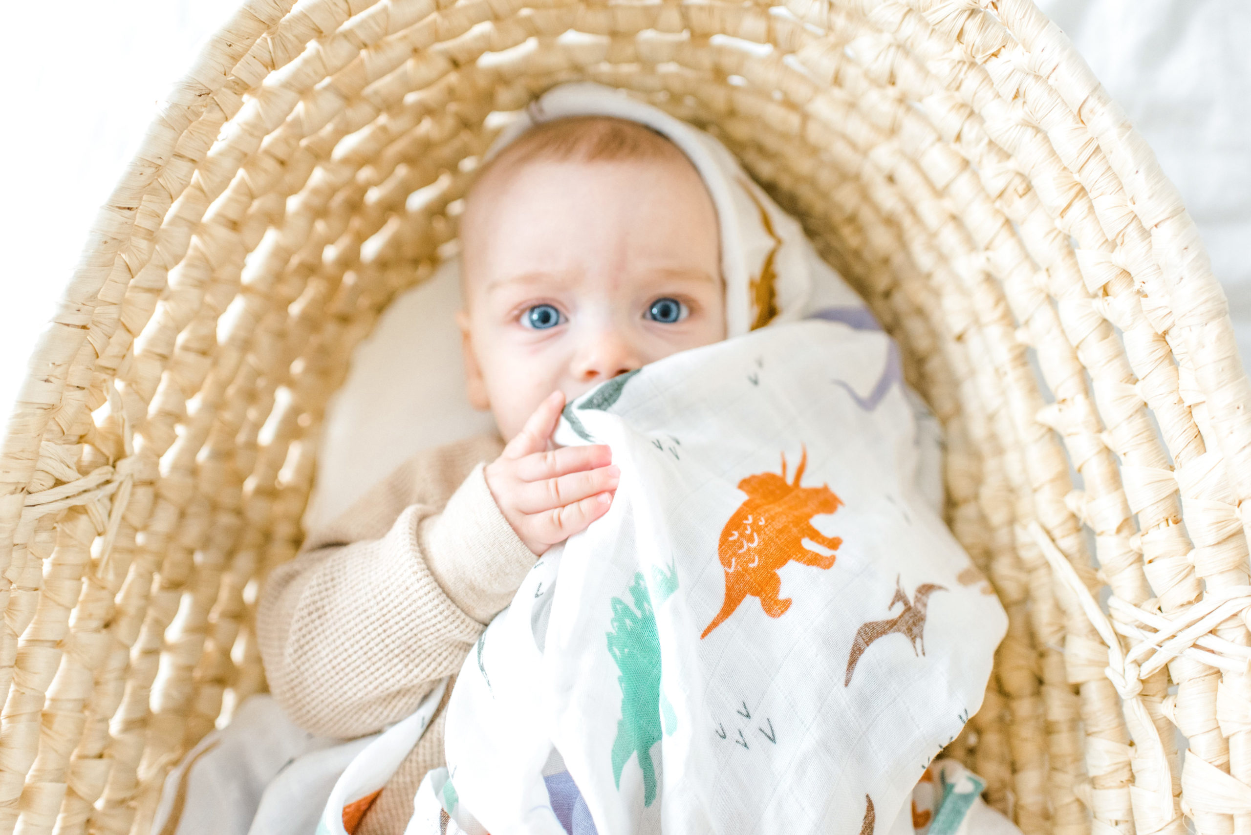 Baby cuddling up with a swaddle for a product photographer.
